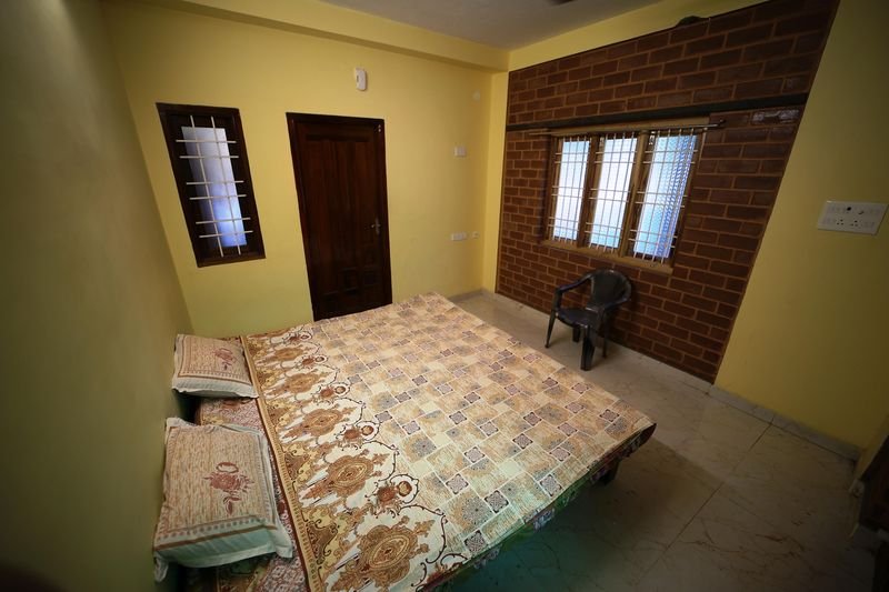Couple room with a double bed, an exposed red-brick wall and wooden door