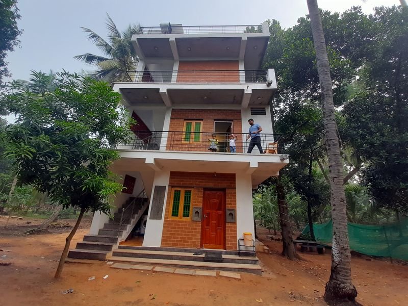 Wide view of the farmhouse front among coconut palms